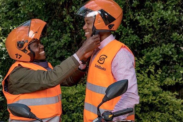 A SafeBoda rider helps a passenger wear a helmet safeboda kenya operations